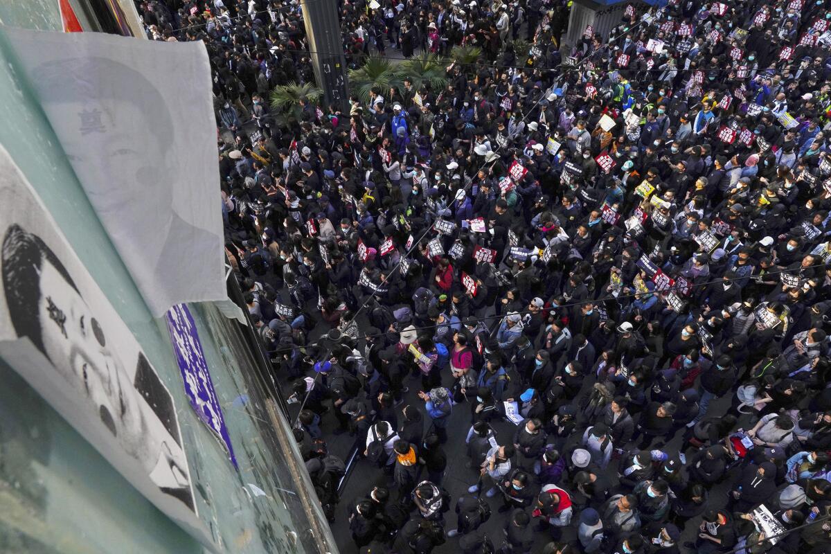 Pro-democracy protesters march past posters depicting Chinese President Xi Jinping on a pedestrian overhead bridge in Hong Kong on Dec. 8, 2019. Thousands of people took to the streets as an anti-government movement prepares to mark half a year of demonstrations.