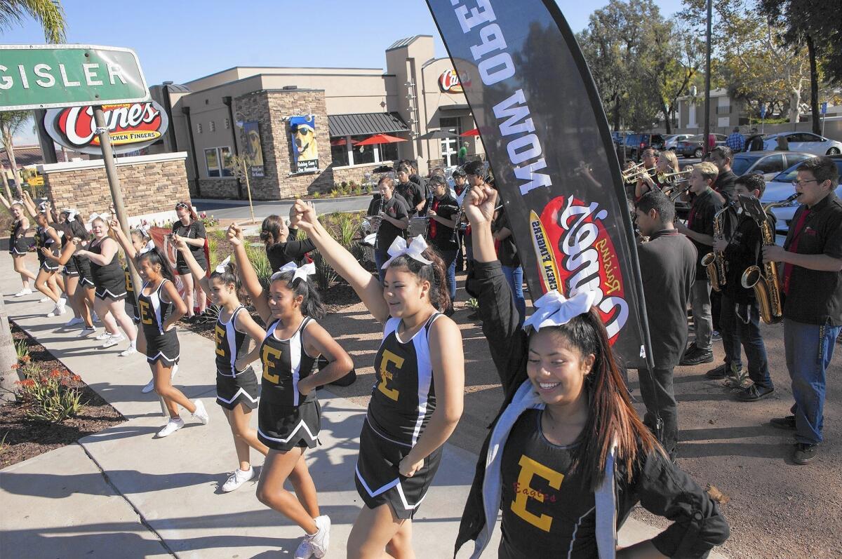 Members of the Estancia High School cheer squad and band perform during the grand opening for Raising Cane's in Costa Mesa on Thursday.