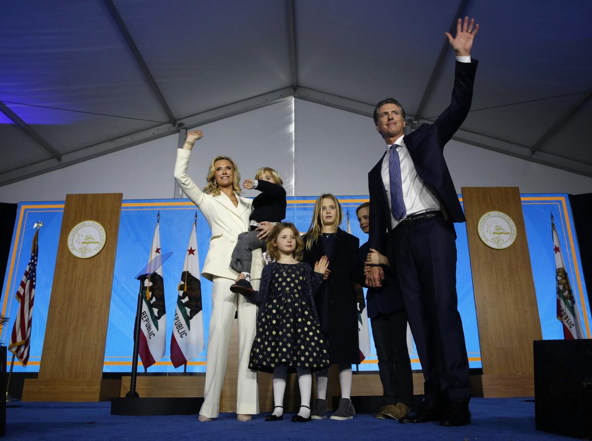 A man waves at the crowd with his family