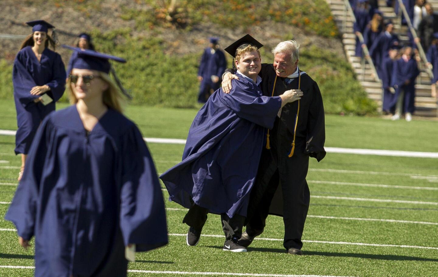 Joe Ahearn, left, hugs Joe Robinson during the 2016 commencement ceremony for Newport Harbor High School at Orange Coast College on Thursday.