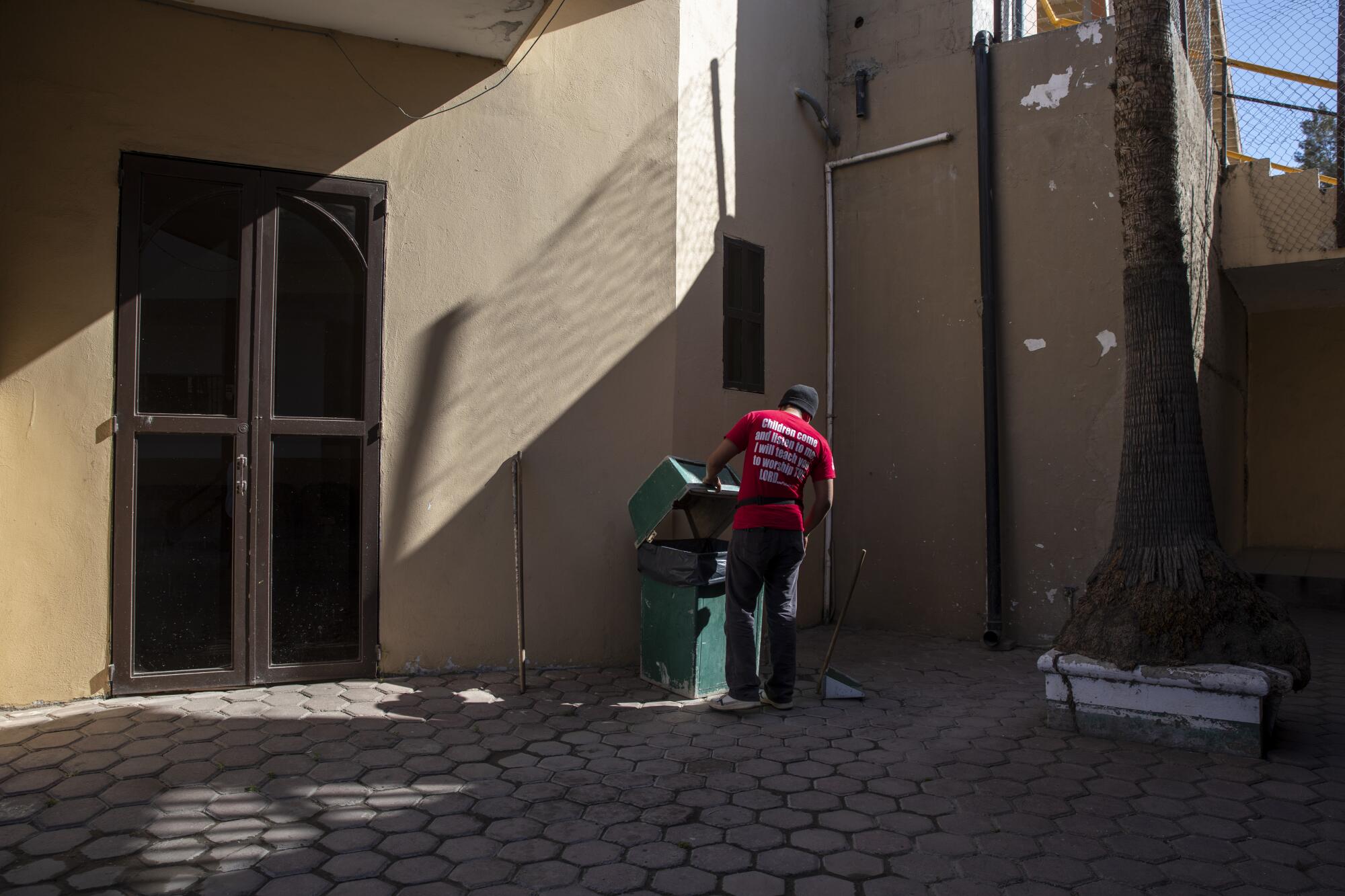 A man dumps trash into a bin outside a building