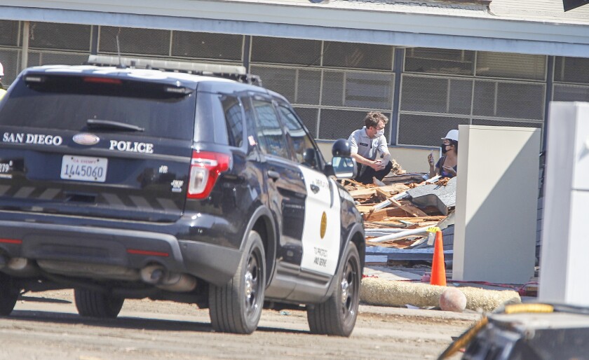 A member of the San Diego Police Department speaks to a woman sitting in building debris