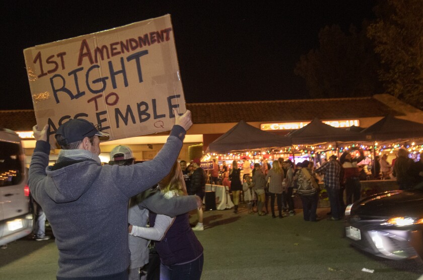 Fines, citations but no compliance: How some restaurants
have defied L.A. County on COVID-19 2 A man holds a sign saying "1st amendment right to assemble" at a protest.