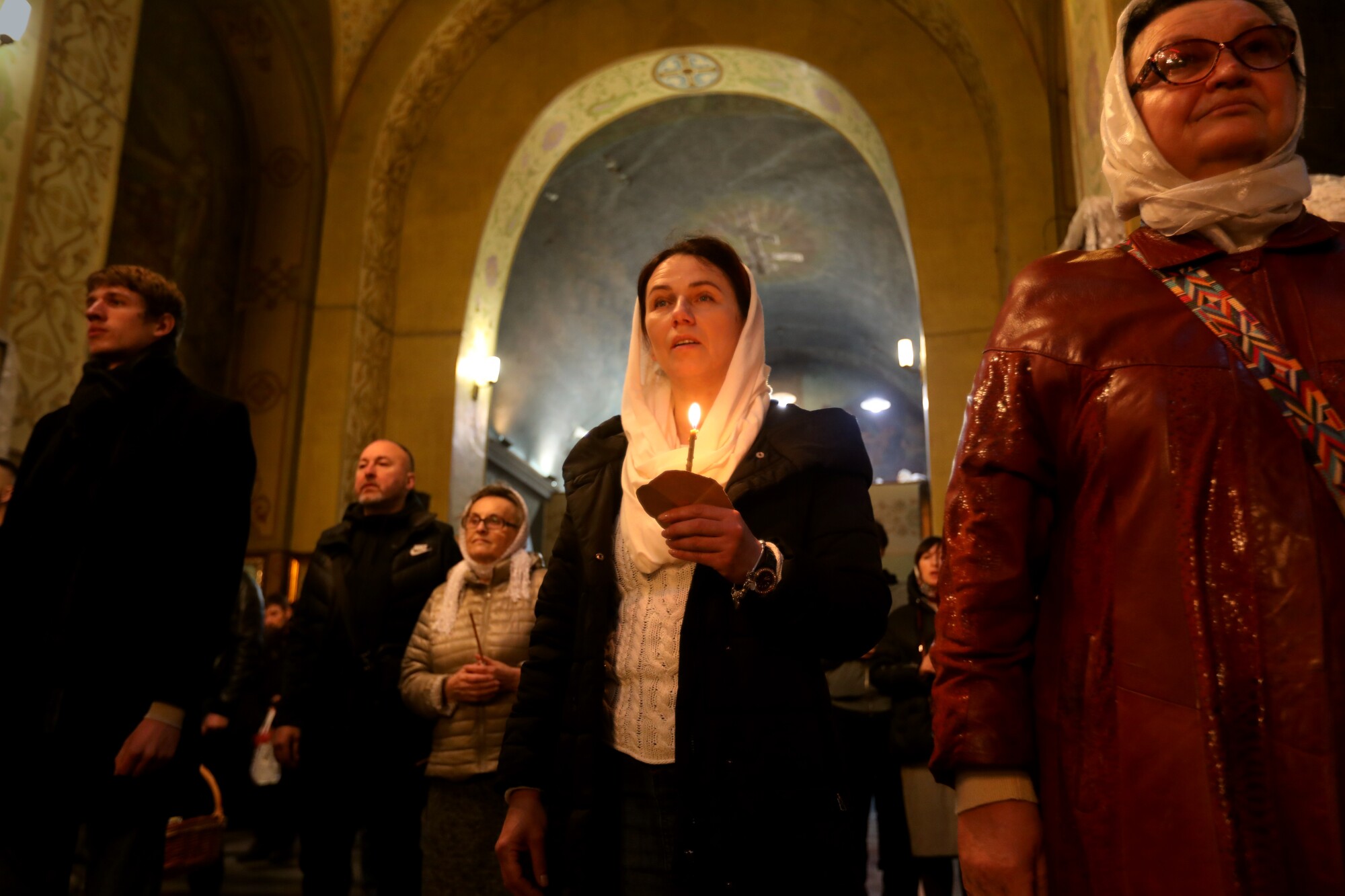 Worshipers stand in a church holding candles.