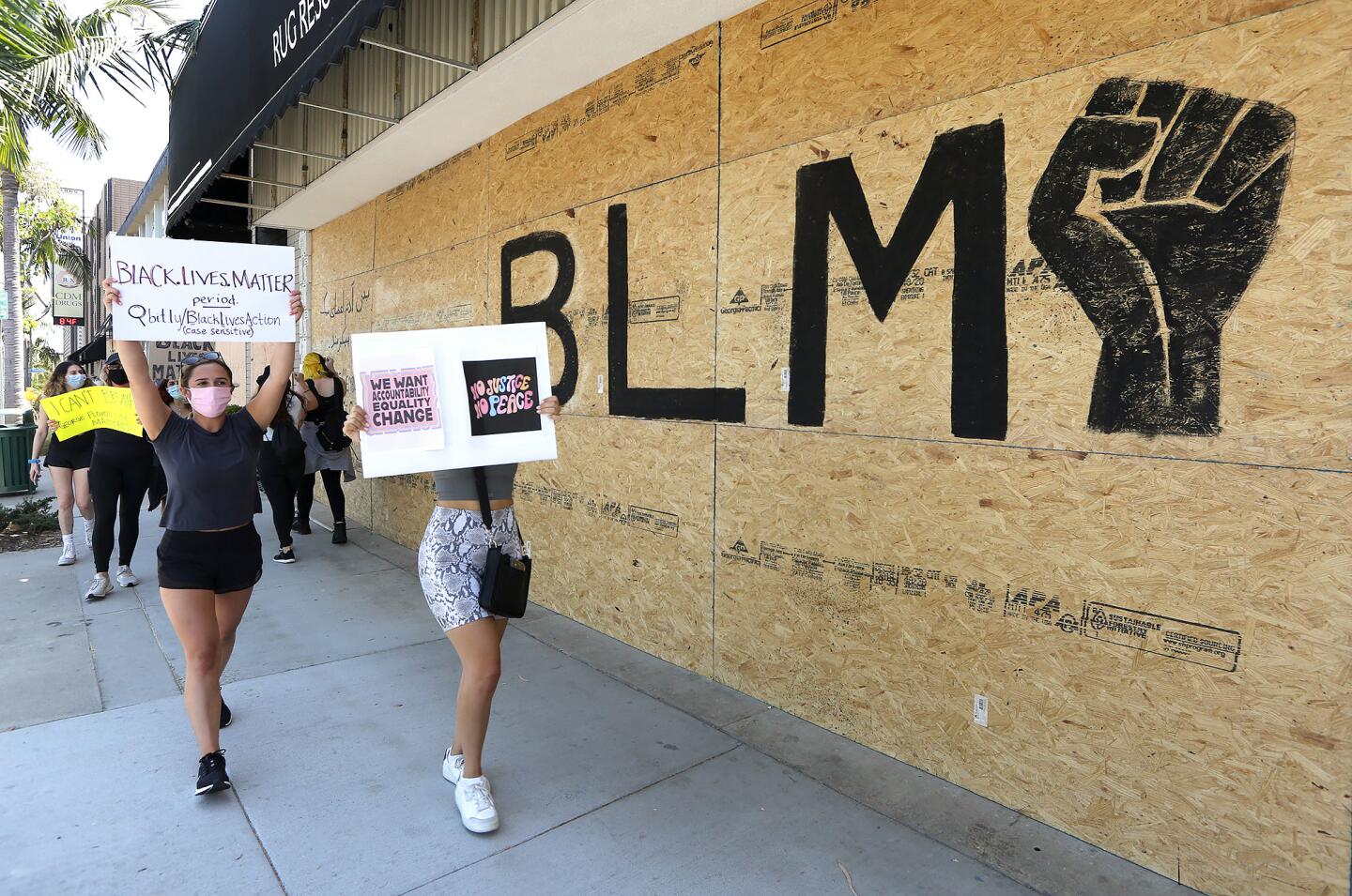 Protesters march past a boarded window at a business in support of the Black Lives Matter protest in Newport Beach on Wednesday.