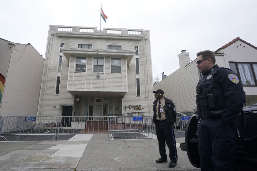 A security guard and San Francisco Police Officer stand in front of the entrance to the Consulate General of India in San Francisco, Monday, March 20, 2023. San Francisco police had erected barriers and parked a vehicle nearby as people protested outside the Consulate General of India to protest the capture of Amritpal Singh. (AP Photo/Jeff Chiu)