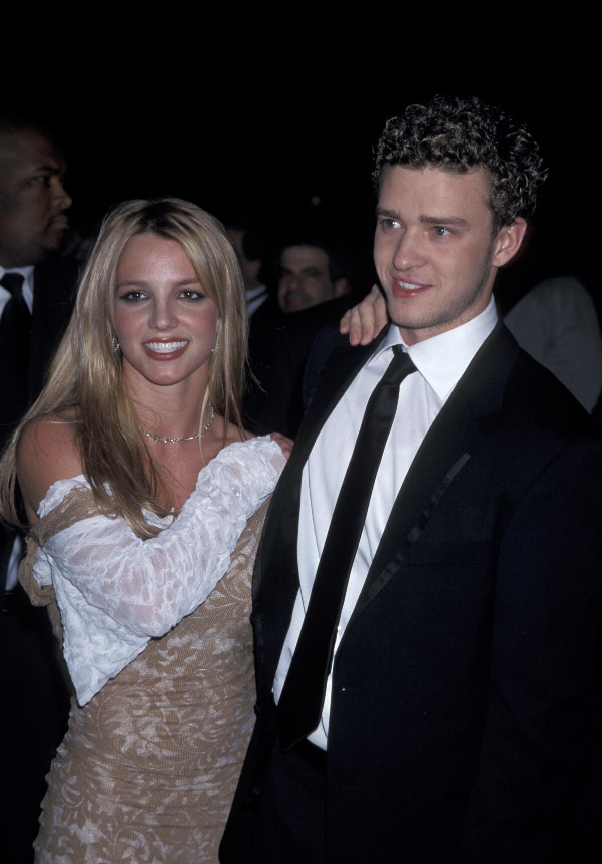 Britney Spears wearing a white and brown dress and Justin Timberlake wearing a suit