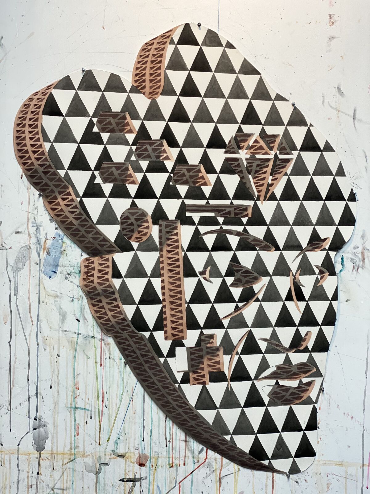 A watercolor shows the outline of a face in a black and white diamond pattern that is seemingly made out of cardboard