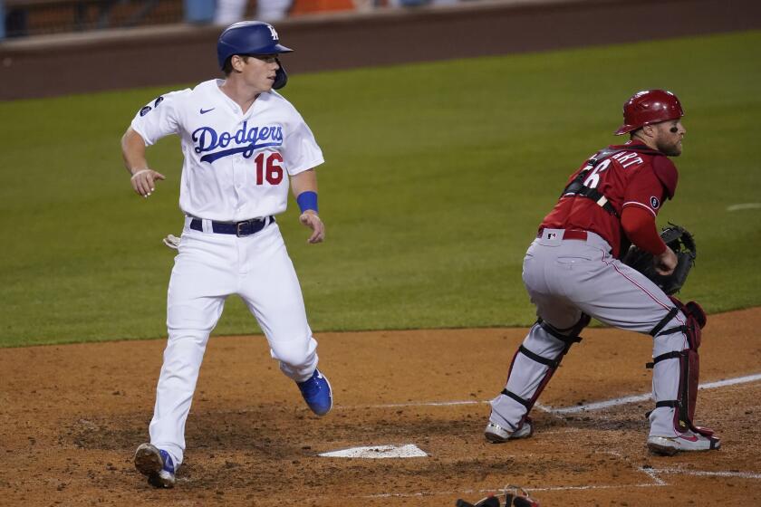 Los Angeles Dodgers' Will Smith (16) scores off of a single hit by Matt Beaty during the sixth inning of a baseball game against the Cincinnati Reds Tuesday, April 27, 2021, in Los Angeles. Cincinnati Reds catcher Tucker Barnhart (16) is at right. Chris Taylor also scored on the play. (AP Photo/Ashley Landis)