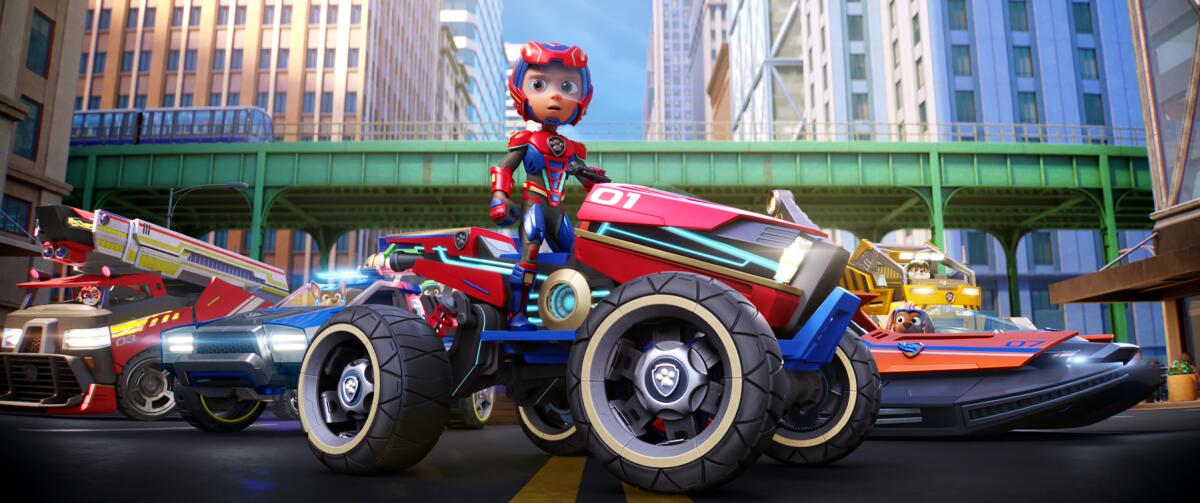 An animated film still shows a boy in a jumpsuit on a futuristic car with huge tires.