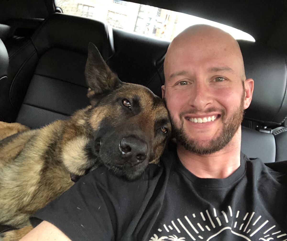 In a vehicle, Abel rests his head on the shoulder of handler Richard Pickett-White.