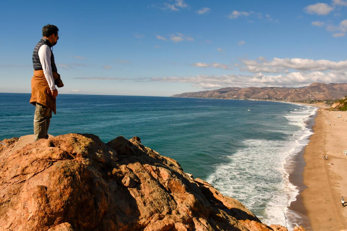 A hiker stands overlooking the beach at Point Dume.
