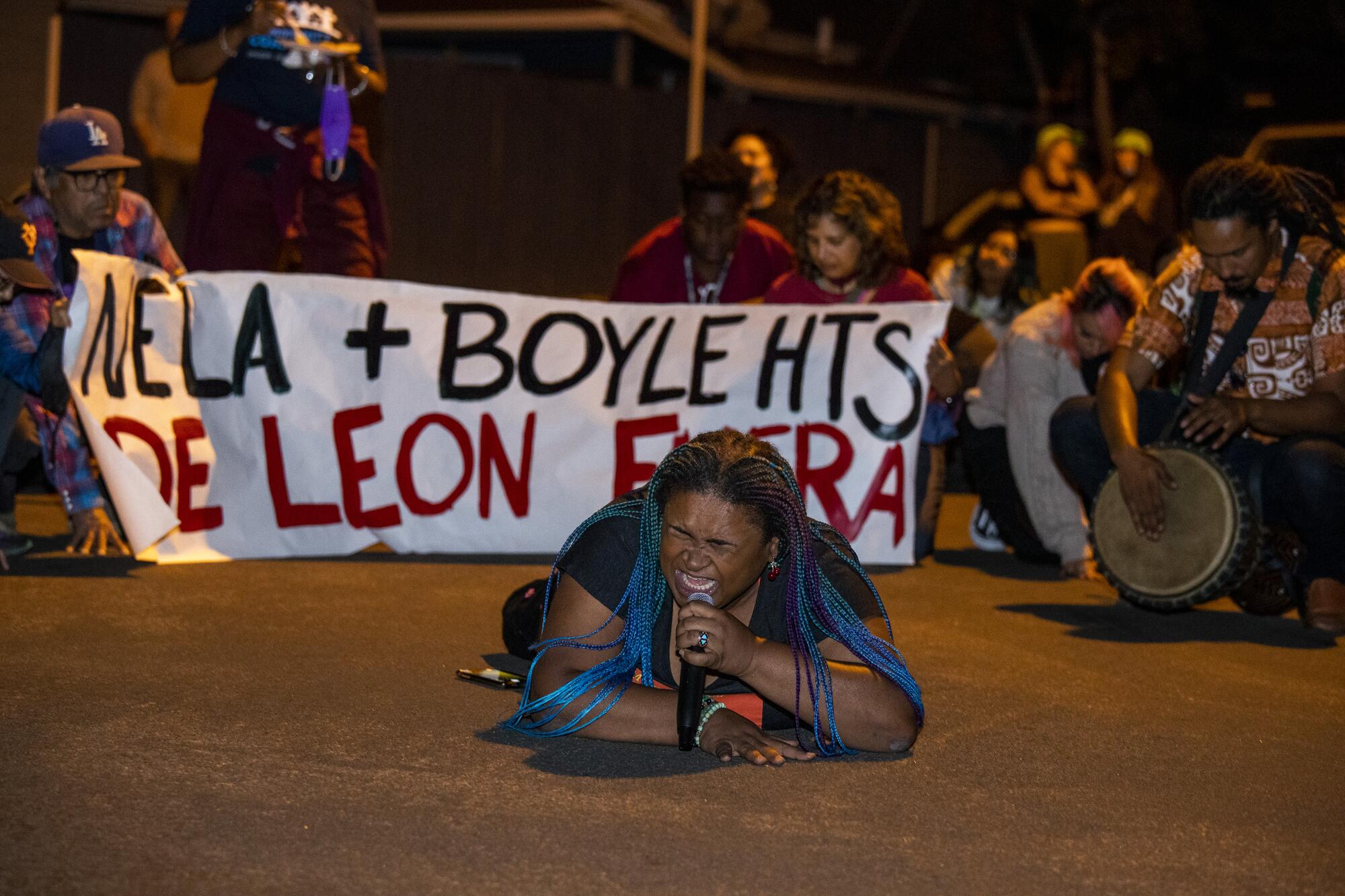 A woman speaks into a microphone while lying on the ground.  