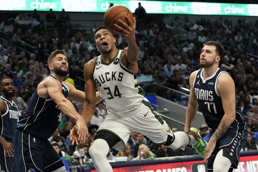 Milwaukee Bucks forward Giannis Antetokounmpo (34) attempts a layup between Dallas Mavericks defenders Luka Doncic (77) and Maxi Kleber, front left, during the first half of an NBA basketball game in Dallas, Friday, Dec. 9, 2022. (AP Photo/LM Otero)