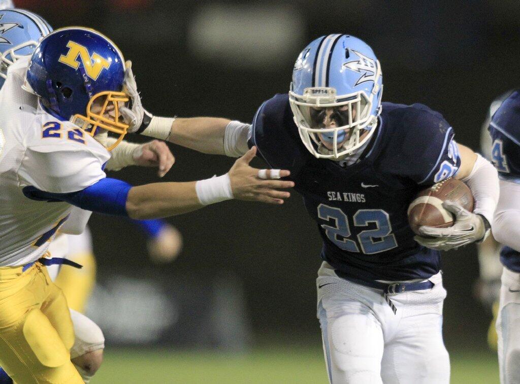 Corona del Mar High's Hugh Crance, right, stiff-arms Nordhoff's Atticus Reyes, left, after recovering a blocked punt during the first half in the CIF State Southern California Regional Division III Bowl Game at LeBard Stadium in Costa Mesa on Saturday.
