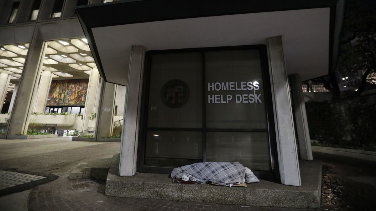 A person sleeps at the Homeless Help Desk, a kiosk in downtown L.A. that provides people with access to information on nearby shelters.
