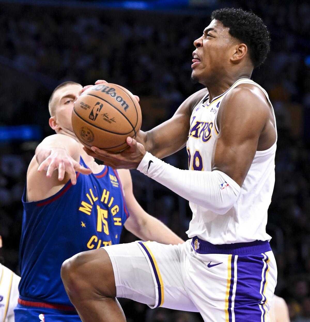 Lakers forward Rui Hachimura, right, elevates for a layup while Nuggets center Nikola Jokic takes a swipe at the ball.