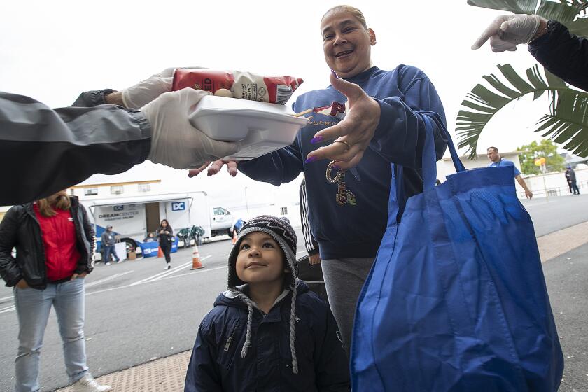 LOS ANGELES, CA-MARCH 16, 2020: Pre K student Jezis Lamb, 4, looks up as his mom, Cynthia Arenas, 42, receives a free lunch to go for him at the Dream Center in Los Angeles. They are from Watts. (Mel Melcon/Los Angeles Times)