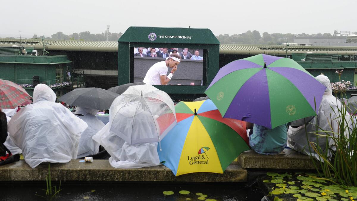 Fans brave the elements as rain interrupts play at Wimbledon on Saturday.