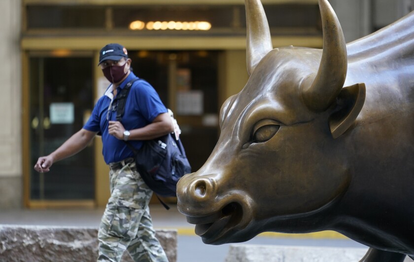 A man wearing a mask passes the Charging Bull statue in New York's financial district.