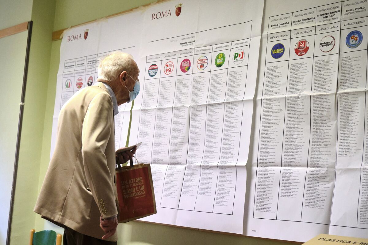 A man looks at candidates' names and party logos at a polling station, in Rome, Sunday, Oct. 3, 2021. Millions of people in Italy started voting Sunday for new mayors, including in Rome and Milan, in an election widely seen as a test of political alliances before nationwide balloting just over a year away. (Mauro Scrobogna/LaPresse via AP)