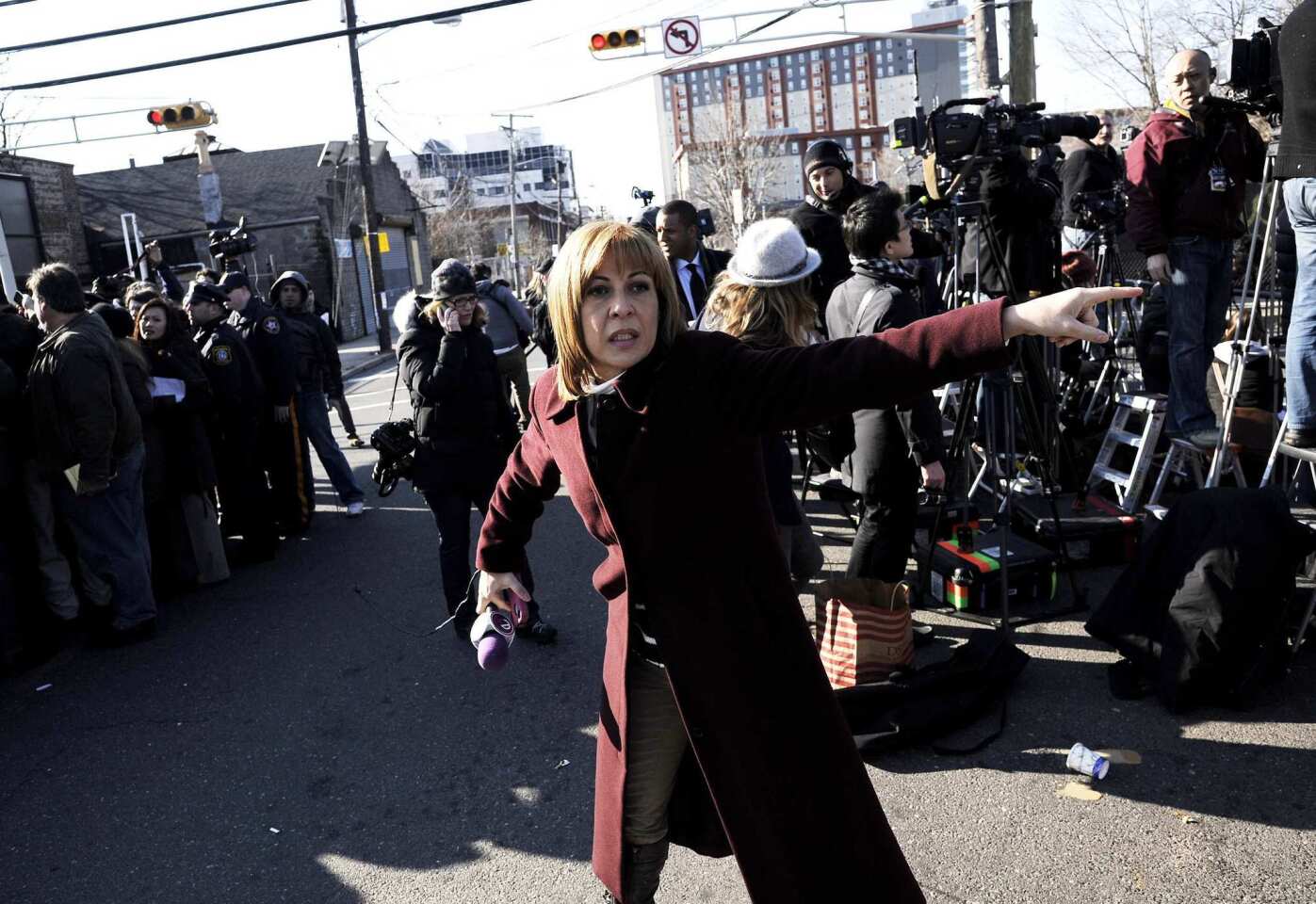 A television reporter yells to her cameraman as photographers watch mourners arrive for Whitney Houston's funeral at the New Hope Baptist church in Newark, N.J.