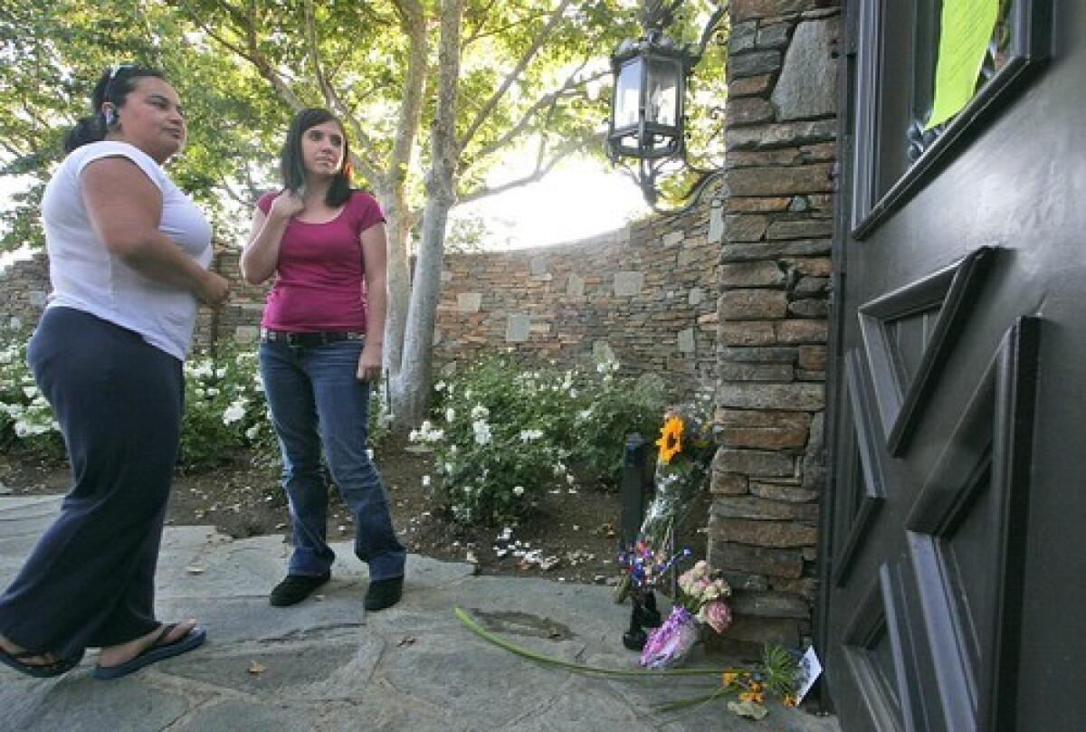 Michael Jackson fans Elia Barbosa, left, and Amanda Tongen read a farewell note at a makeshift memorial at the gates of the pop icon's old Neverland Ranch, in Los Olivos, Calif. Jackson died Thursday in Los Angeles at the age of 50.