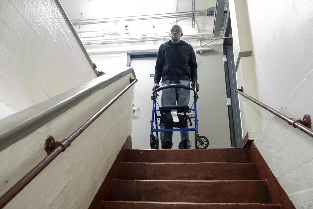  Kenneth Owens, 70, standing at the steps with his walker inside the SRO Madison Hotel in Los Angeles