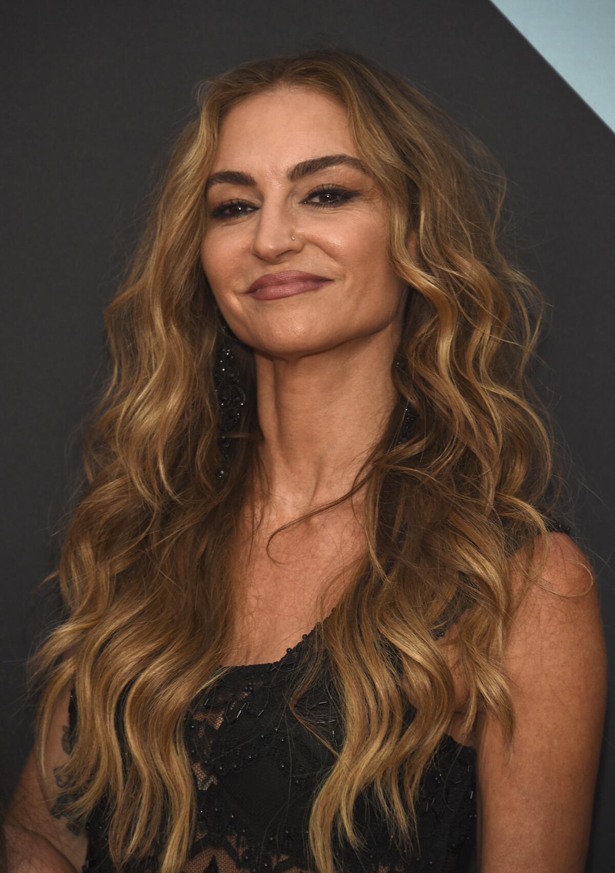 Drea de Matteo shows off a crooked smile and long hair while wearing a sleeveless black dress