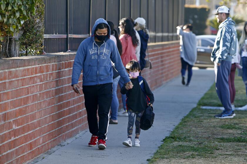 A parent walks his son to class on Tuesday morning at Hope View Elementary in Huntington Beach. Mask requirement for California classrooms will be lifted after March 11.