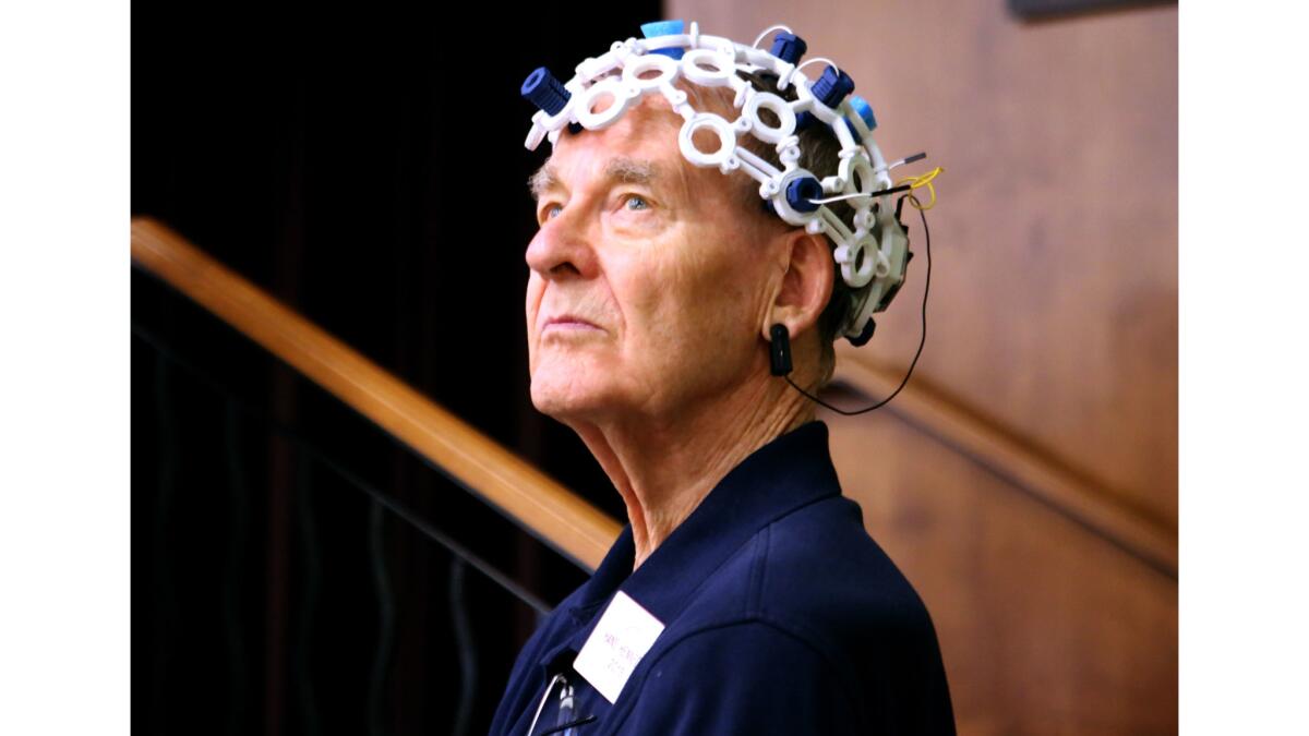 By concentrating on an audio frequency while wearing a 3-D printed device on his head, senior citizen Hans Hennecke was able to turn on a lightbulb during a demonstration by Cal State Fullerton engineering students at Morningside of Fullerton on April 12.