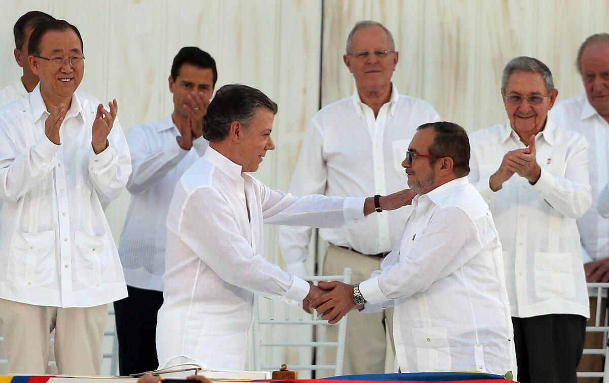 El presidente de Colombia, Juan Manuel Santos, a la izquierda, y el máximo comandante de las Fuerzas Armadas Revolucionarias de Colombia, Rodrigo Londoño, alias “Timochenko”, se dan la mano tras la firma del acuerdo de paz entre el gobierno colombiano y las FARC para poner fin a más de 50 años del conflicto en Cartagena, Colombia, el lunes 26 de septiembre del 2016. (Fernando Vergara/AP Foto)