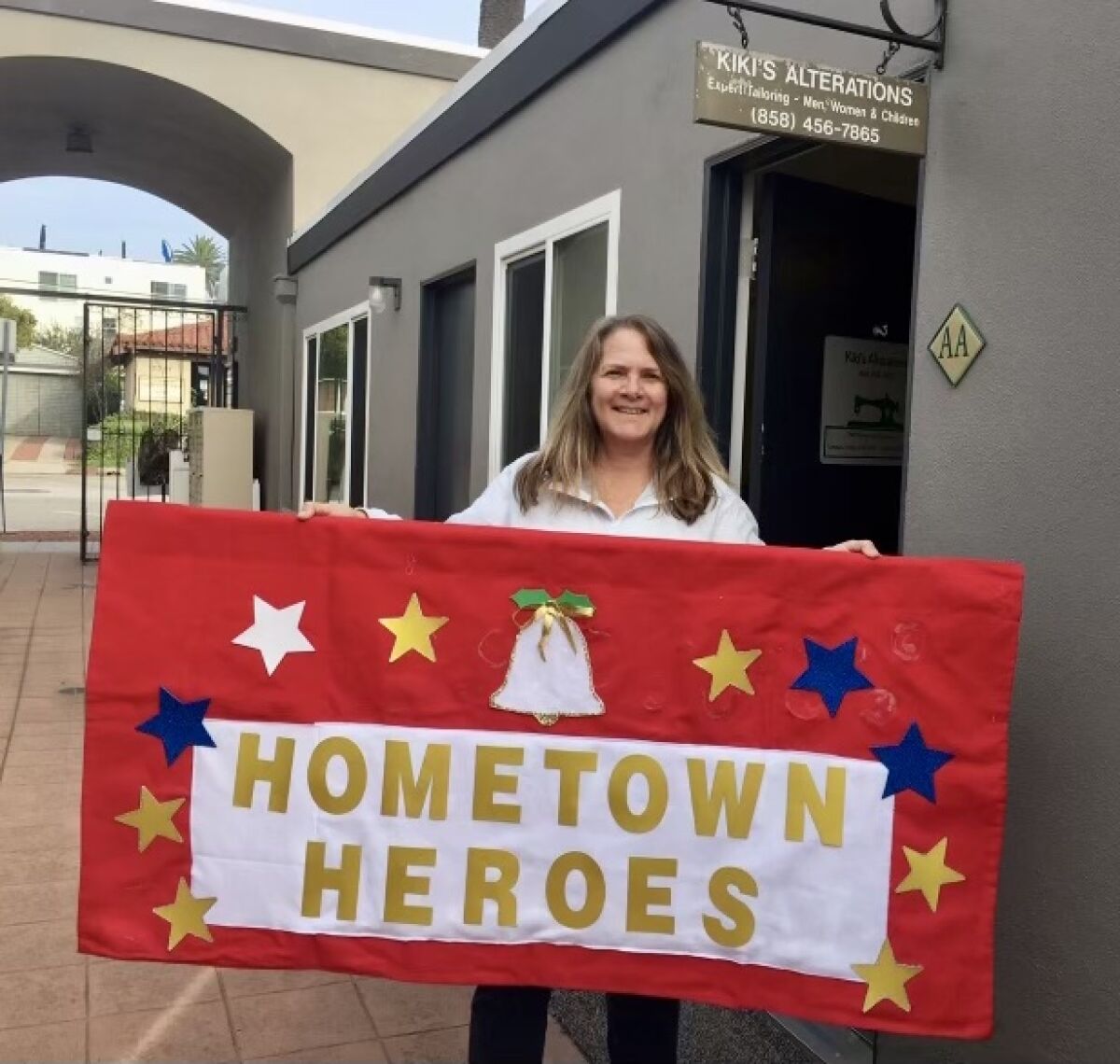 Tammy Spounias of Kiki's Alterations in La Jolla holds the banner the company donated for the 2021 La Jolla Christmas Parade.