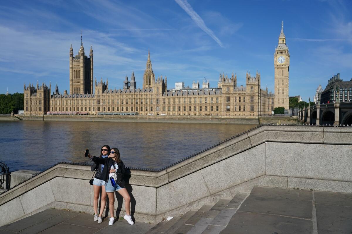 Two people take a selfie opposite the Houses of Parliament in London, Friday July 15, 2022. The British Meteorologic office issued a red warning for extreme heat, advising of a "potentially very serious situation" in parts of England next week.(Dominic Lipinski/PA via AP)