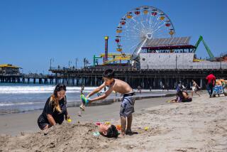 Santa Monica, CA - June 21: Gracie Morales of El Paso Texas and her brother Noah bury their other brother George in the sand as they enjoy the first day of summer at the beach near the Santa Monica Pier as sunshine finally returns to the southland on Wednesday, June 21, 2023 in Santa Monica, CA. (Jason Armond / Los Angeles Times)
