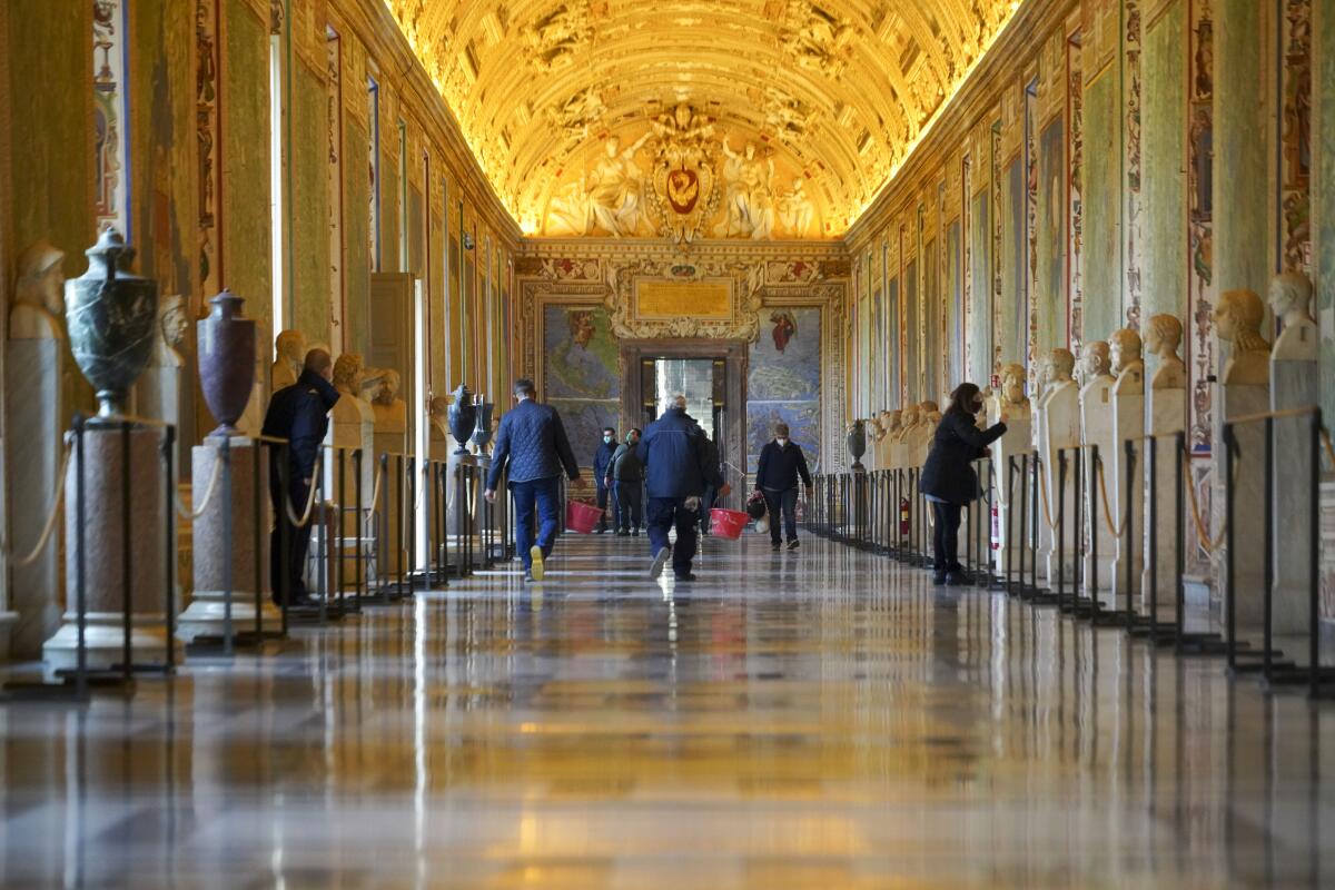 ARCHIVO - Trabajadores de museo caminan por un pasillo de los Museos Vaticanos