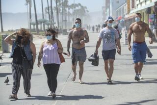 VENICE, CA-MAY 14, 2020: Background left to right-Friends Joshua Andrew, 32, of Chicago, Illinois, Bryan Hawn, 32, and Vlad Parker, 29, both of Santa Monica, wear masks to protect against the coronavirus while walking with others doing the same along the boardwalk in Venice Beach. A new rule, announced by Mayor Eric Garcetti on Wednesday, now requires face masks for all outdoor activities. (Mel Melcon/Los Angeles Times)