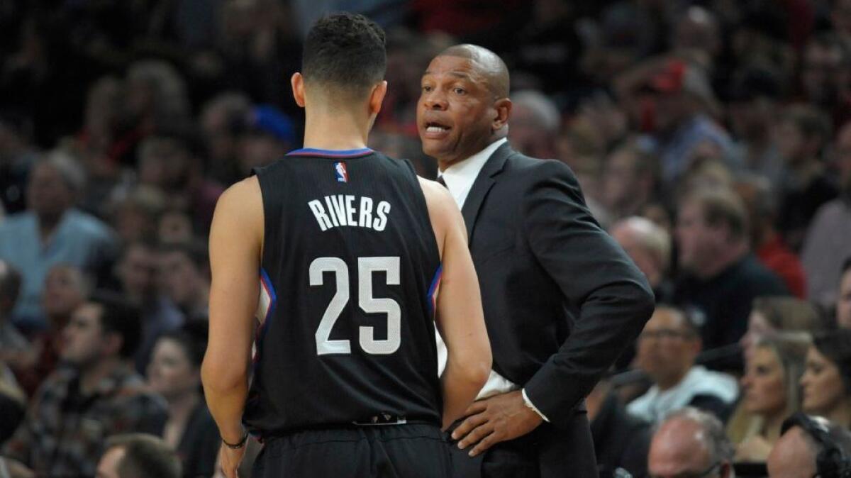 Clippers Coach Doc Rivers talks with his son, Austin Rivers, during the team's season-opening 114-106 victory over the Portland Trail Blazers on Oct. 27.
