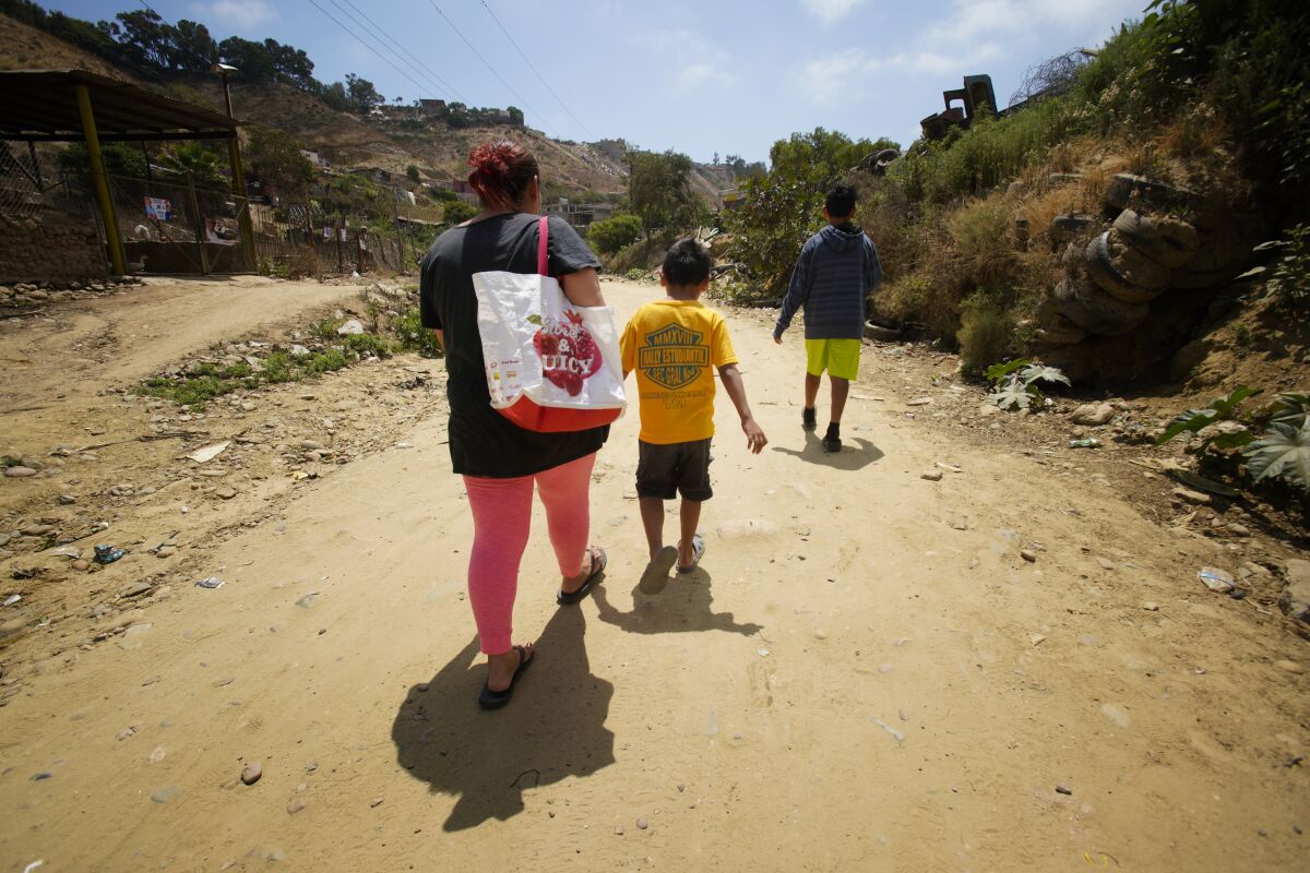 Antonia Portillo, 44, and her two children, Jon and Christian, walk back to the Embajadores shelter where they have been staying in Tijuana on Thursday. Portillo always keeps her children with her because she believes they will be kidnapped. She has submitted her paperwork asking for asylum in the U.S. and is currently waiting in Tijuana for her federal court date scheduled in July.