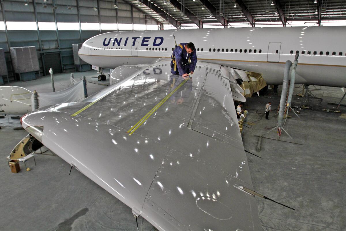 Jonathan Mauro applies safety markers on the wings of a Boeing 777. United Airlines is reportedly considering installing ten seats per row in the economy section.
