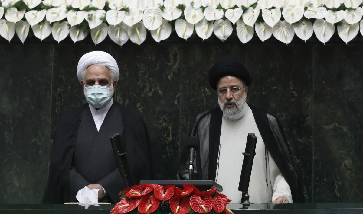 President Ebrahim Raisi, right, takes his oath as president, as Judiciary Chief Gholamhossein Mohseni Ejehi listens in a ceremony at the parliament in Tehran, Iran, Thursday, Aug. 5, 2021. Raisi, a protégé of Iran's supreme leader, completes hard-liners' dominance of all branches of government in the Islamic Republic. (AP Photo/Vahid Salemi)