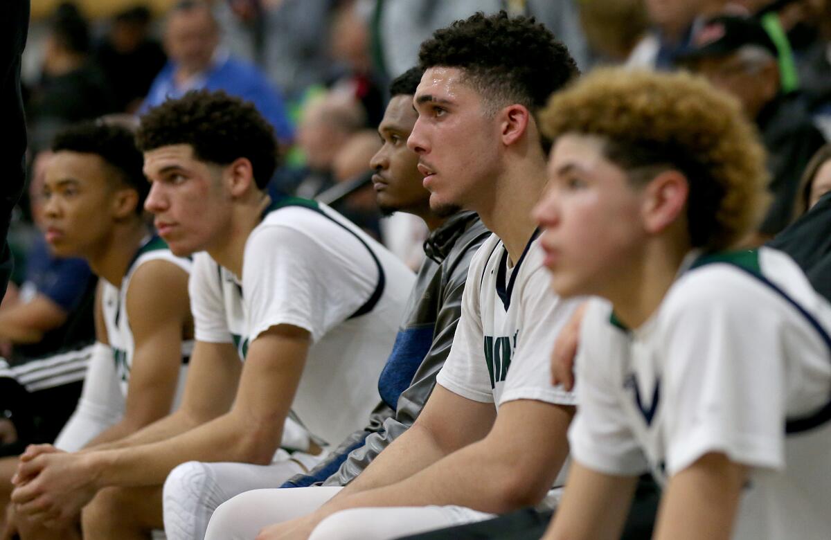 LiAngelo Ball is flanked by his brothers Lonzo and LaMelo sit on the bench.