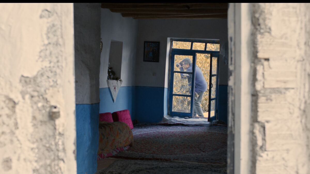 A man using a camera is seen through a doorway