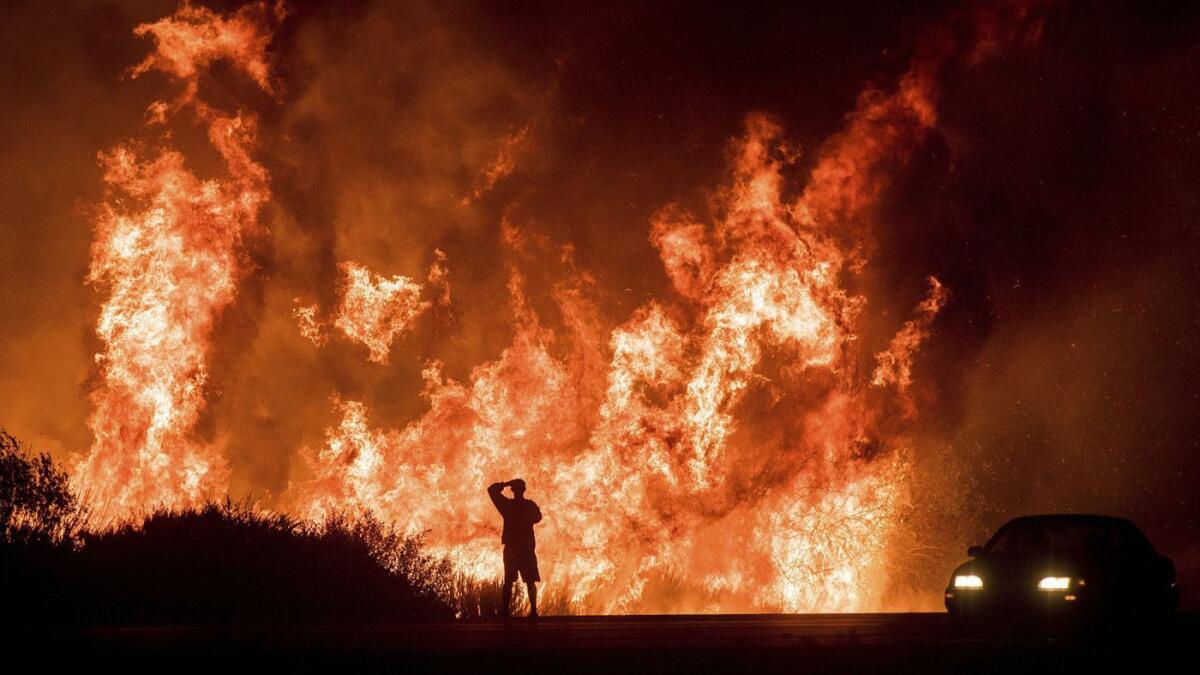 A motorist on Highway 101 watches flames from the Thomas fire in December.