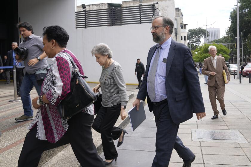 Jesus Maria Casal, president of the Opposition Primary Commission, front right, arrives to the Attorney General's office where he was summoned about the opposition's recent primary elections in Caracas, Venezuela, Monday, Oct. 30, 2023. Prosecutors have opened a criminal investigation into primary organizers on charges including identity fraud and usurping authority and the government has maintained a ban on the primary winner from running for office. (AP Photo/Ariana Cubillos)