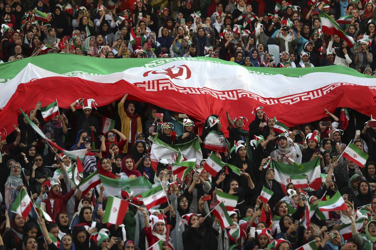 Iranian women holding an Iranian flag cheer