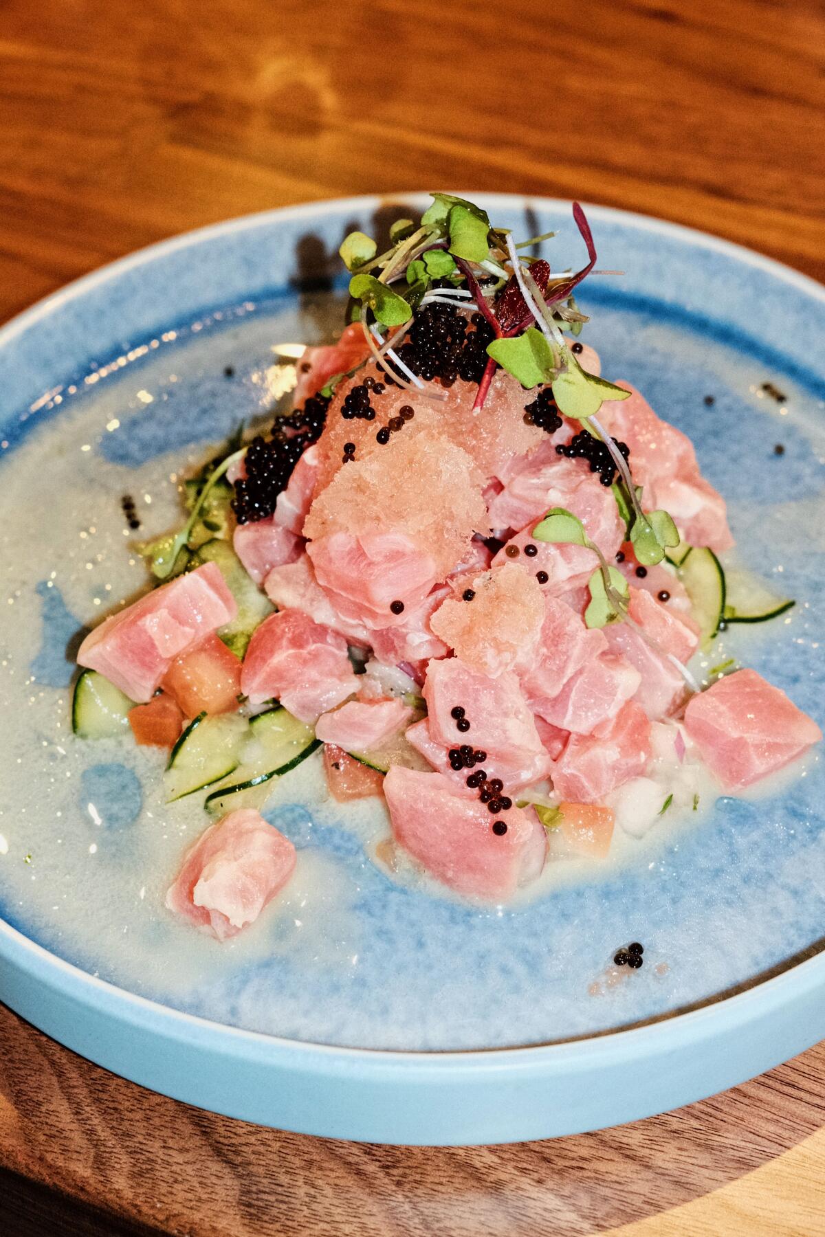 Tuna sinimak crudo with coconut milk, spiced vinegar and guava granita on a blue plate at Manila Inasal.