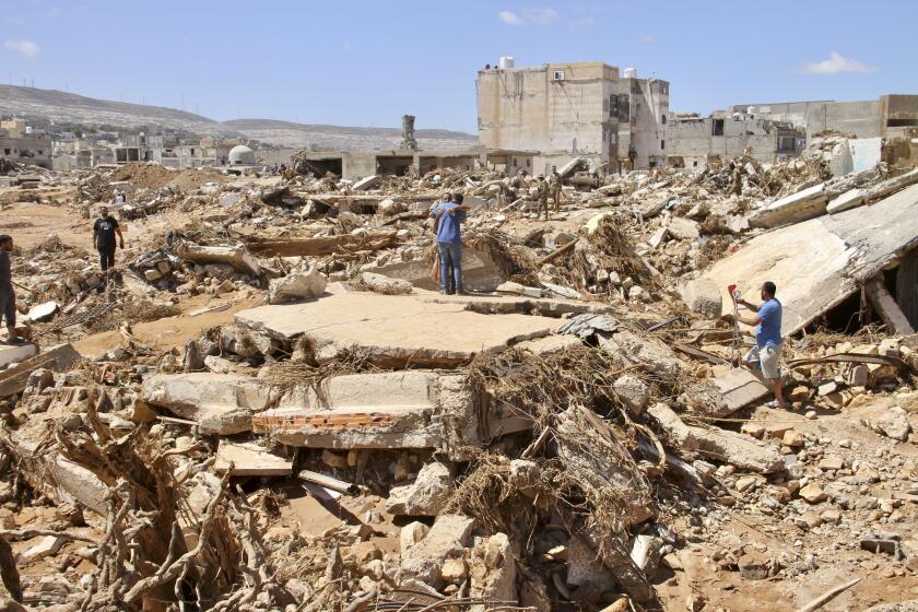 People look for survivors in Derna, Libya, Wednesday, Sept.13, 2023. Search teams are combing streets, wrecked buildings, and even the sea to look for bodies in Derna, where the collapse of two dams unleashed a massive flash flood that killed thousands of people. (AP Photo/Yousef Murad)