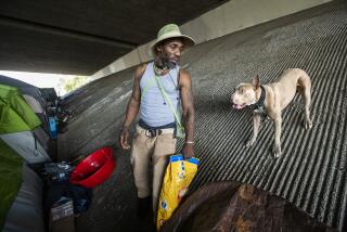 PACOIMA, CA-JULY 22, 2019: Josh Morgan, 27, prepares to feed his dog, Shop, at a homeless encampment located under the 118 fwy in Pacoima. Caltrans wants to oust everyone from this location, but it has been delayed due to a legal challenge. (Mel Melcon/Los Angeles Times)