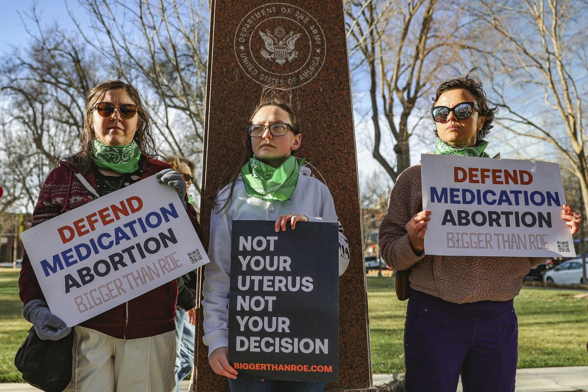 Three members of the Women's March group protest in support of access to abortion medication 